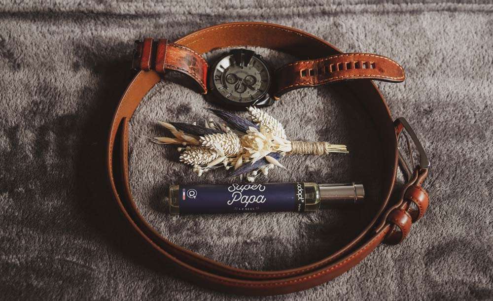 composition faite avec des accessoires du marié ; sa ceinture qui forme un cercle , sa montre, sa boutonnière et son parfum