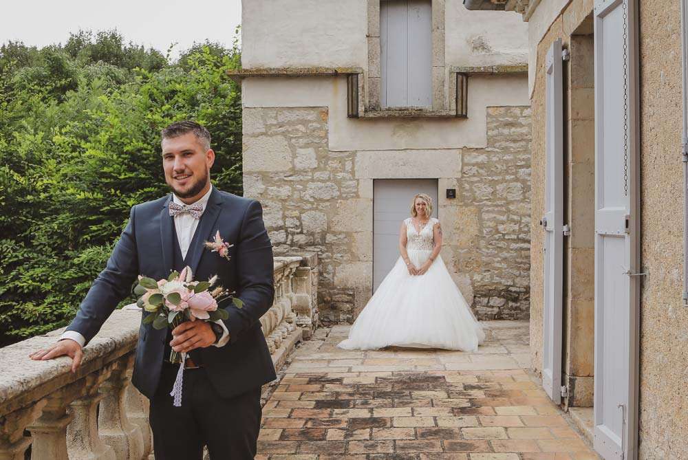 le marié dos à sa femme attend avec le bouquet à la main de découvrir la future mariée