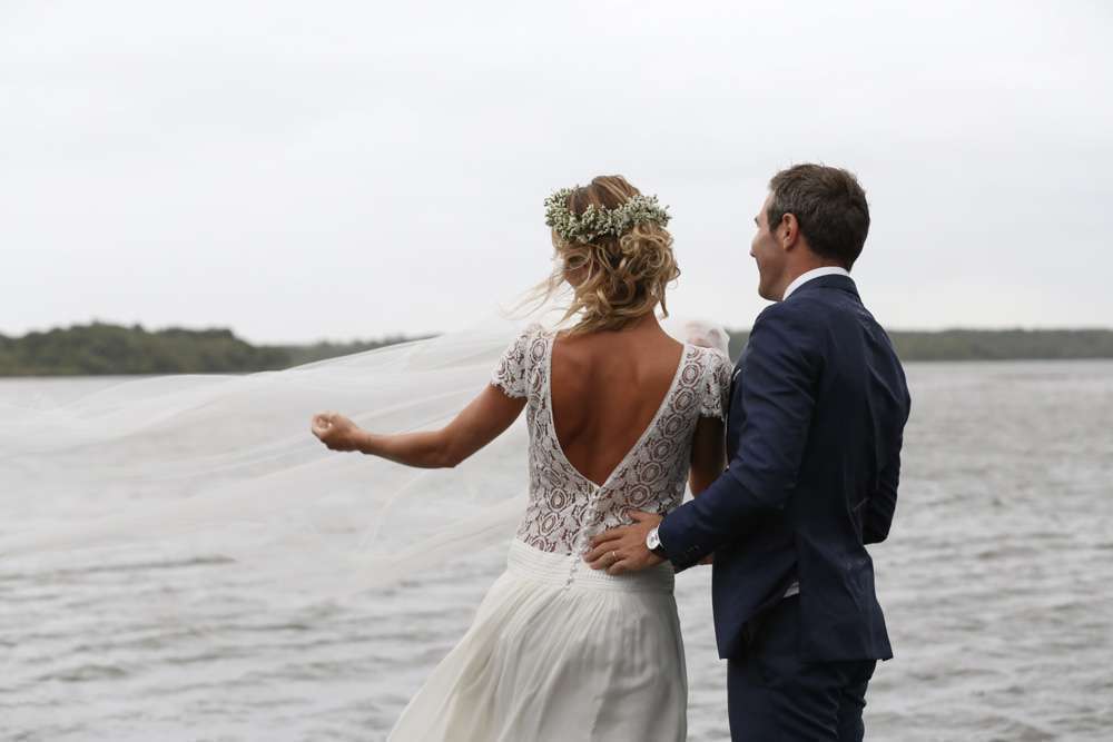 sur le ponton du lac, il pleut la marié fait voler au vent son voile et son mari la regarde