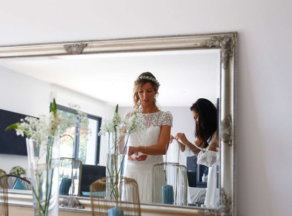 Reflet de la mariée dans un miroir pendant qu'elle ajuste un bracelet
