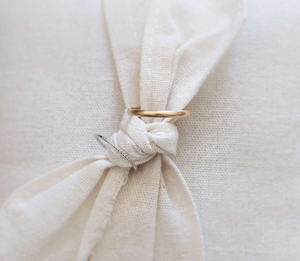 les anneaux des mariée tenus dans un noeud de lin sur un coussin de présentation