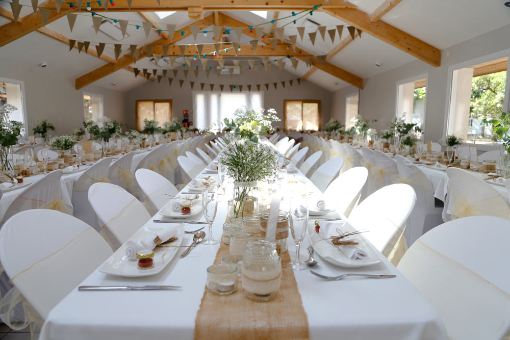 jolies tables de mariage dréssées avec des nappes blanches, toile de jute et fleurs des champs naturelles